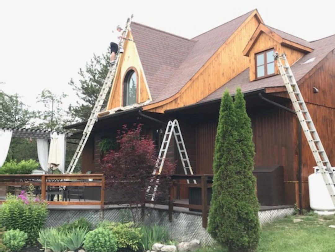 Ladders set up against the gable end of a house during an exterior repaint